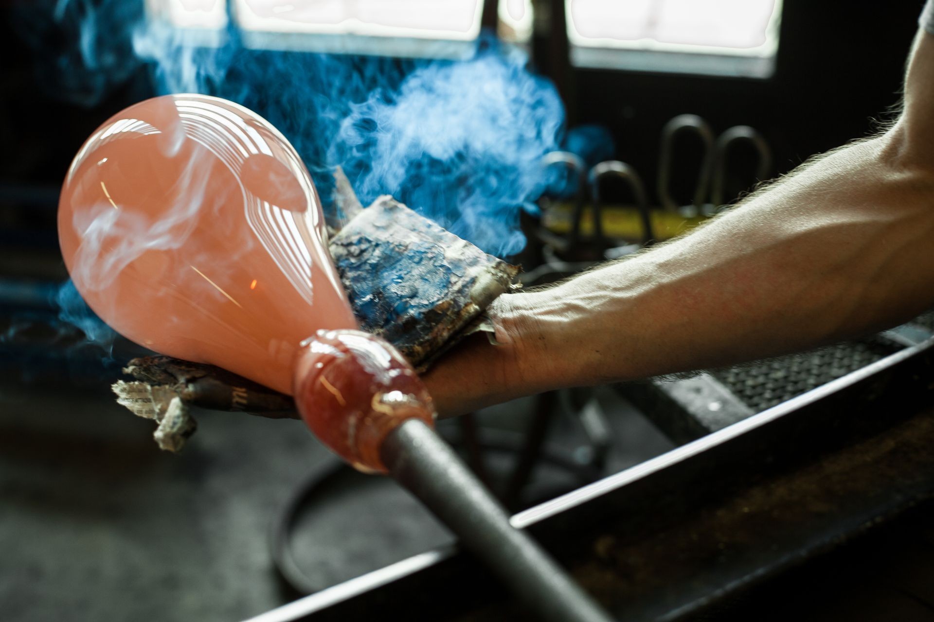 Glass-blower man working with hot ocher glass to make a blown glass lantern Glass-blower man working with hot ocher glass to make a blown glass lantern
